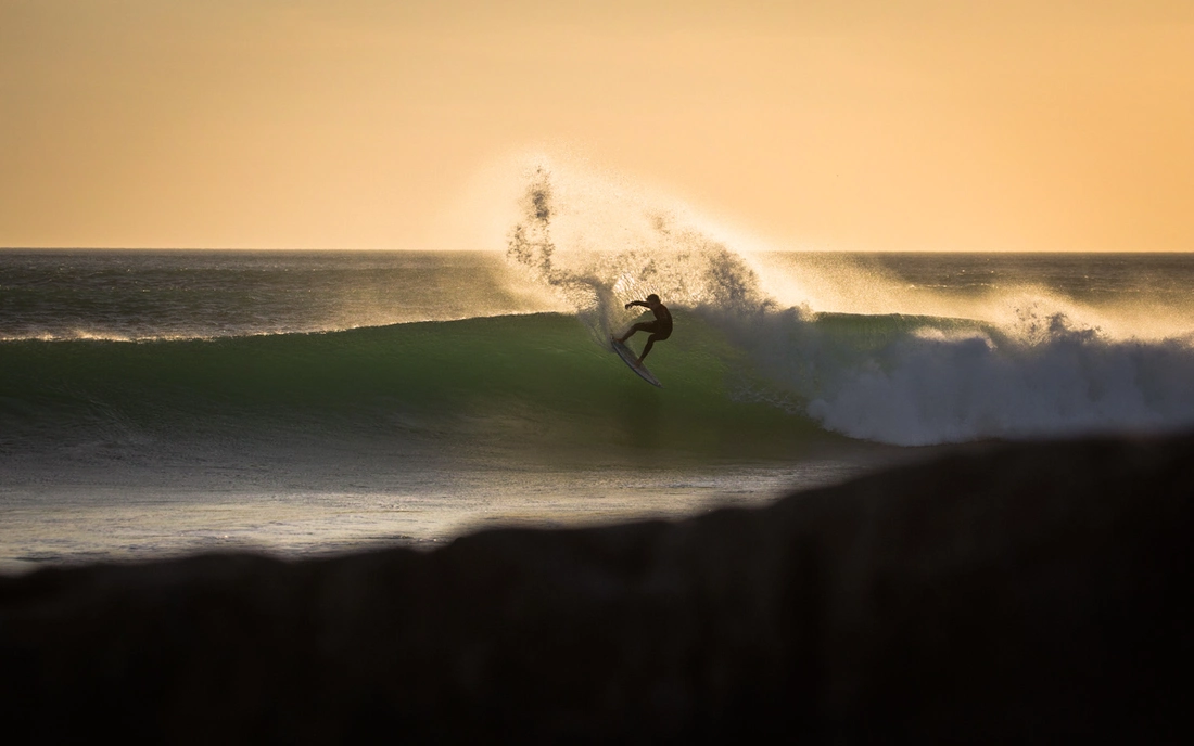 surfer surfing wave during sunset in morocco