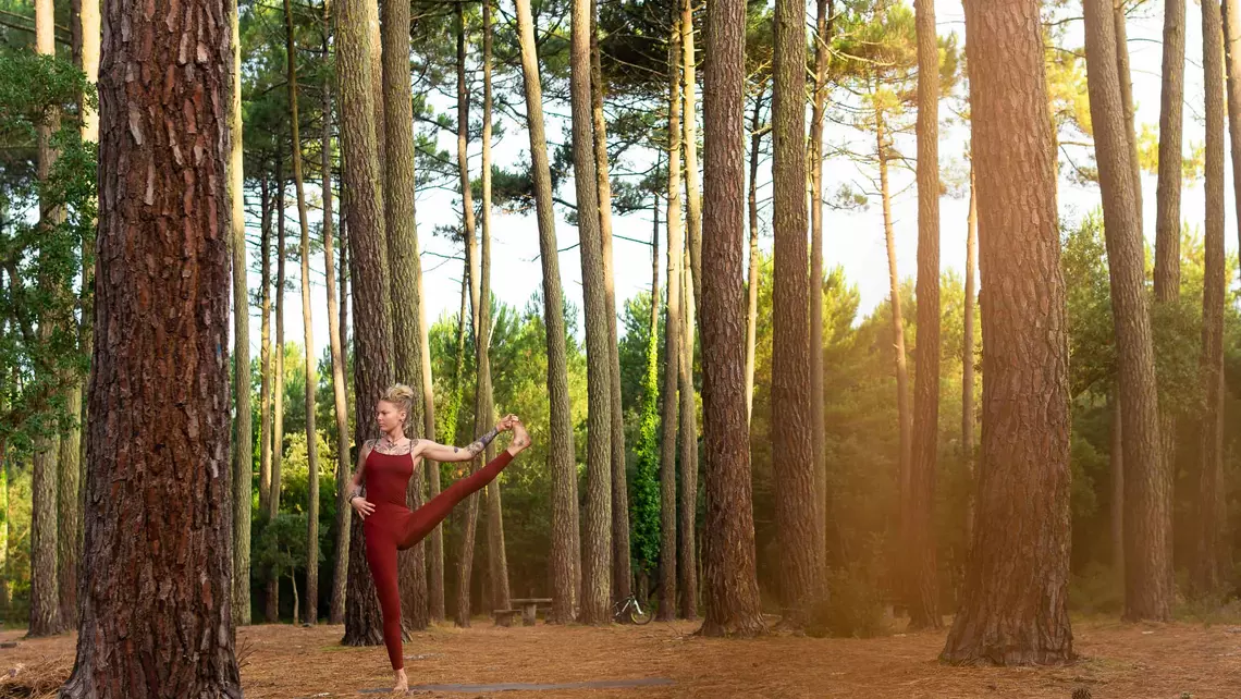 Yoga-Lehrerin in Yogapose im Pinienwald