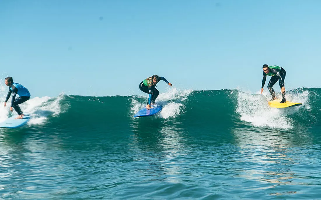 Mehrere Surfer im Surfkurs beim Surfen lernen