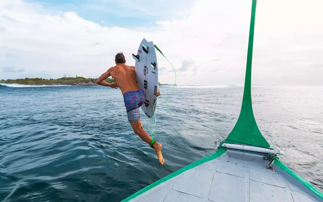 Surfer springt von Boot ins Wasser