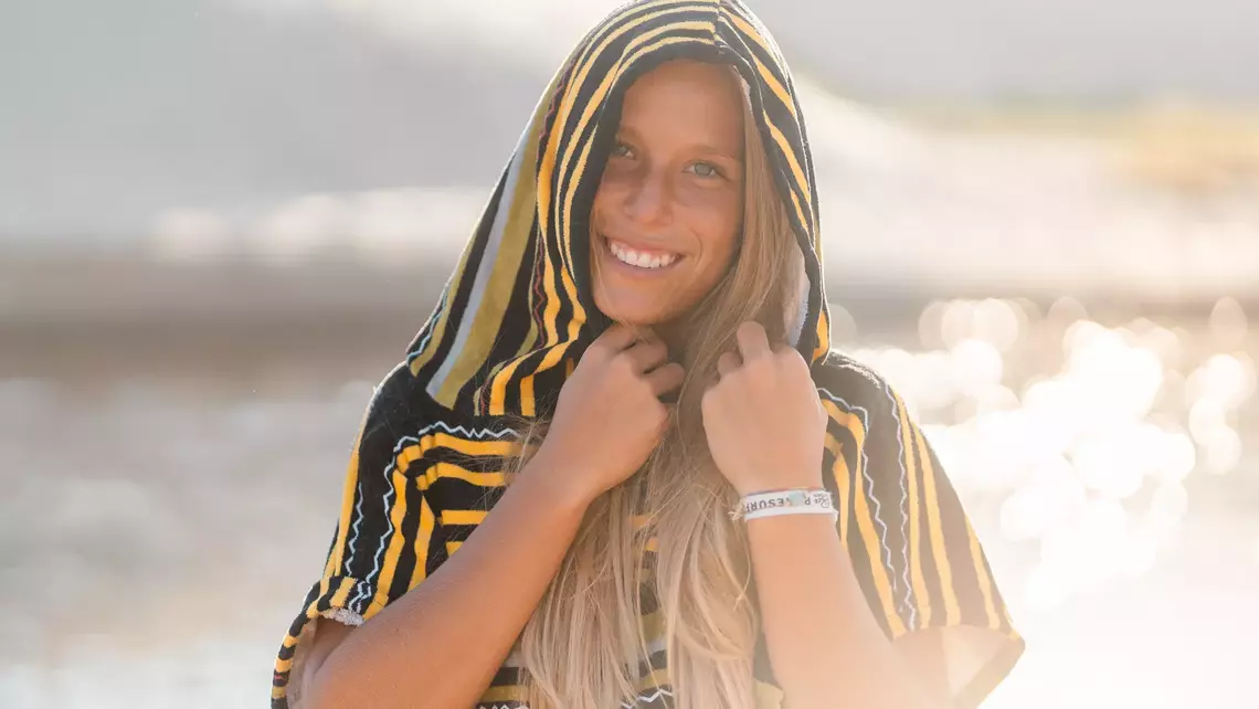 Surferin im Surf Poncho mit Kapuze am Strand