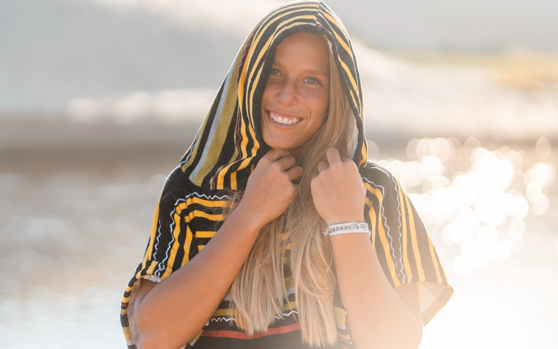 Surferin im Surf Poncho mit Kapuze am Strand