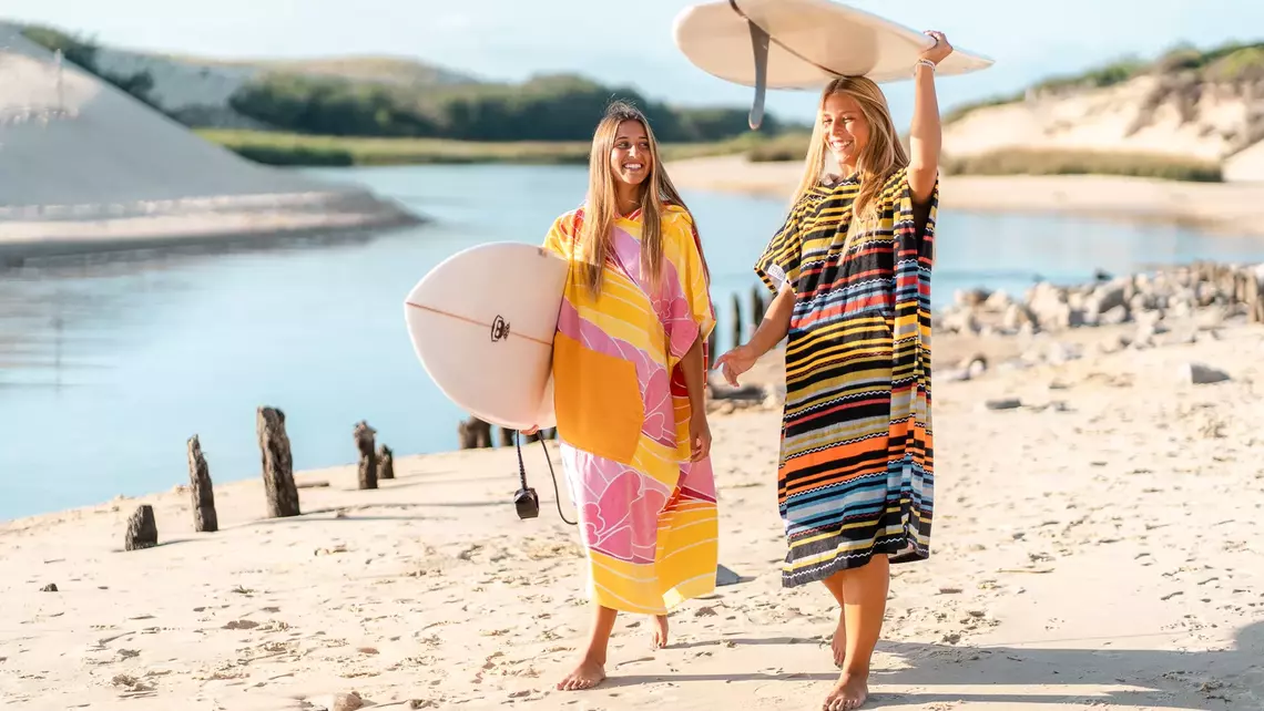 Surferinnen im Surf Poncho und mit Surfbrett am Strand