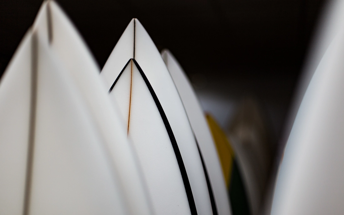 Weiße Surfbretter mit spitzer Nose in einer Reihe