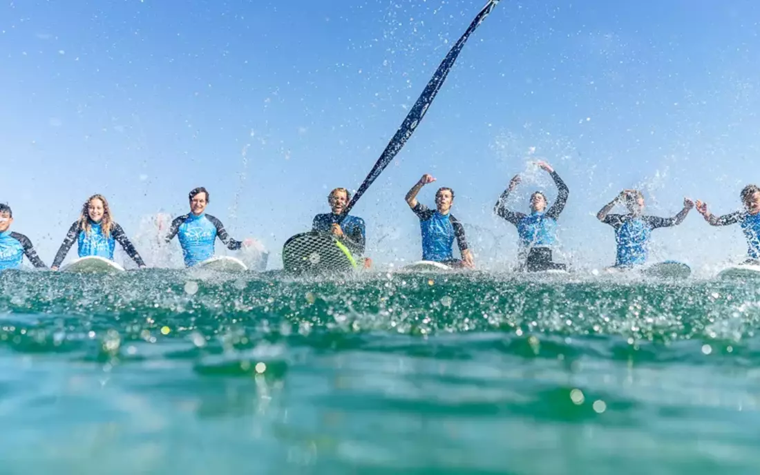 Surflehrer mit Surfkurs auf Surfbrettern im Wasser