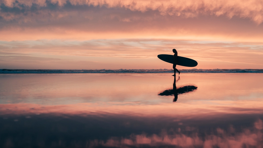 Surfer bei Sonnenuntergang am Strand