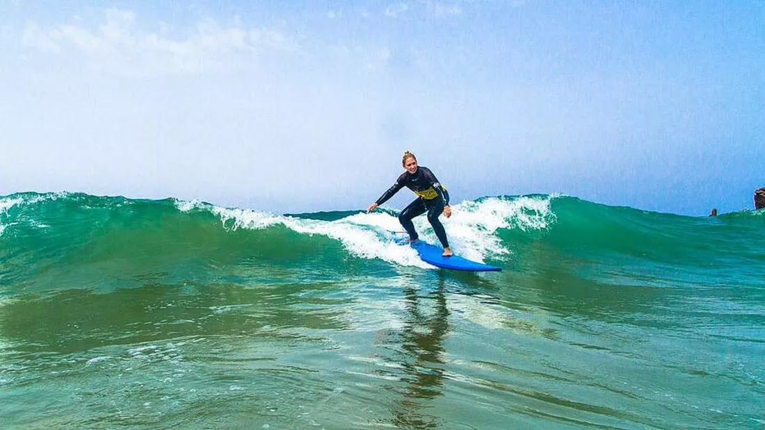 Surfer surft gruene Welle im Surfkurs