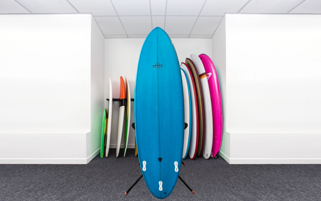 Blaues Surfbrett vor einer Reihe Surfboards