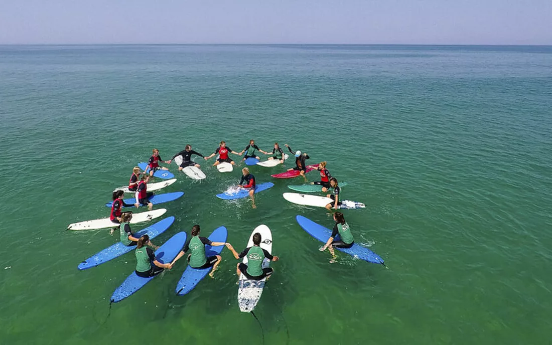 Surfschule beim Unterricht im Kreis sitzend