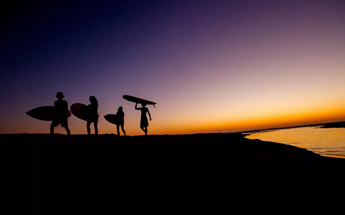 Surfer nach Surfkurs bei Sonnenuntergang am Strand