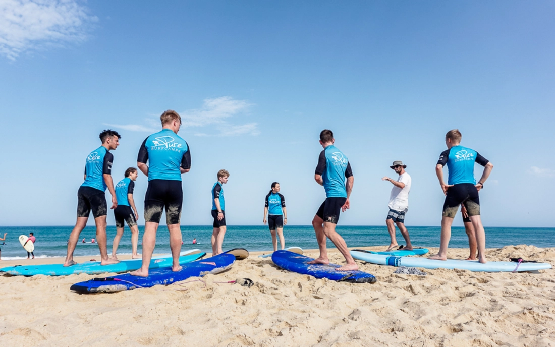 Surfkurs mit Surflehrer beim Aufwärmen am Strand