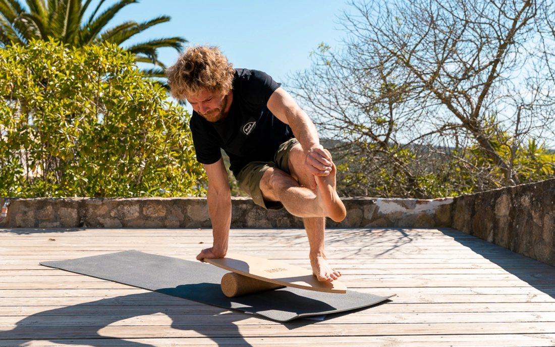 Mann beim Surfworkout auf Balance Board aus Holz mit Korkrolle