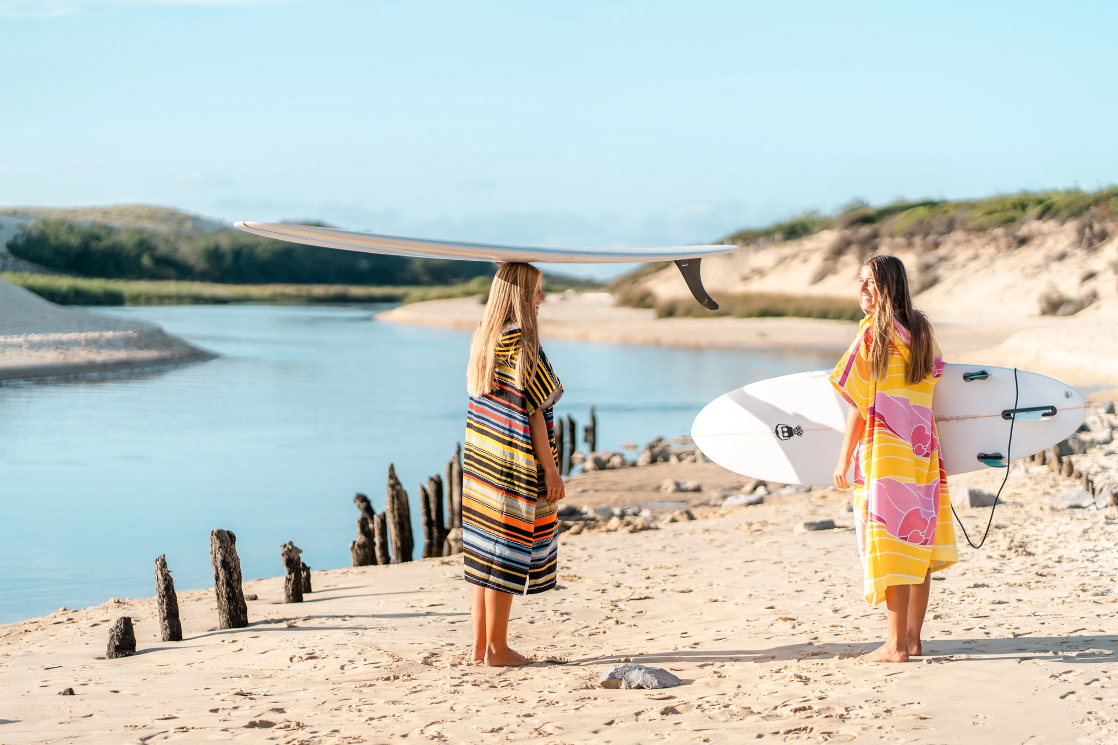 Surferinnen im Surf Poncho und mit Surfbrettern am Strand