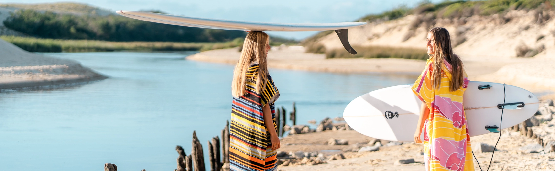 Surferinnen im Surf Poncho und mit Surfbrettern am Strand