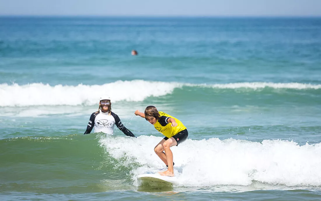 Surfschule mit Surflehrer und Kind im Wasser