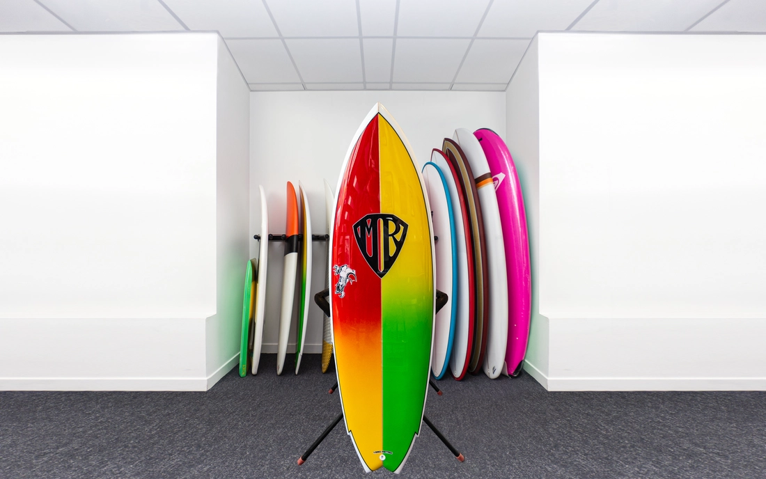 Buntes Performance Fish Surfbrett vor einer Reihe Surfboards