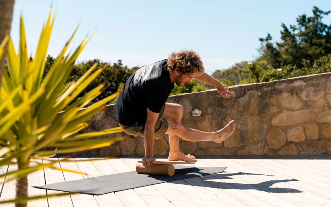 Mann beim Surfworkout auf Balance Board aus Holz mit Korkrolle