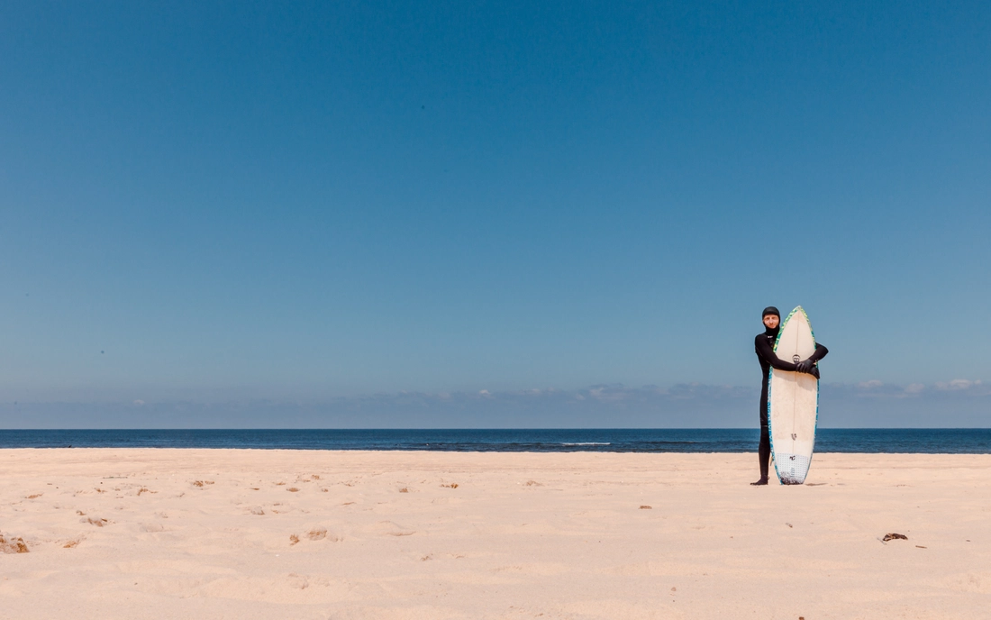 Surfer im Hooded Neoprenanzug am Strand