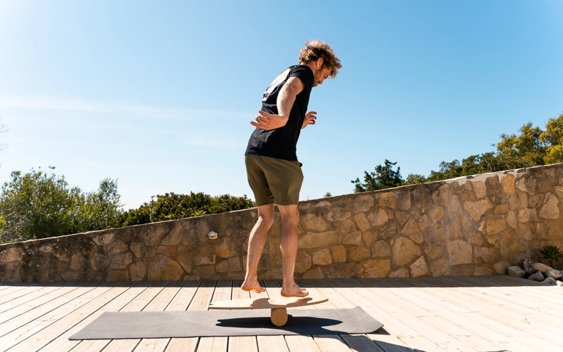 Mann beim Surfworkout auf Balance Board aus Holz mit Korkrolle