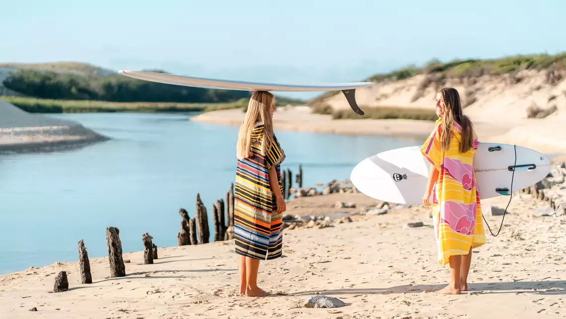 Surferinnen im Surf Poncho und mit Surfbrett am Strand