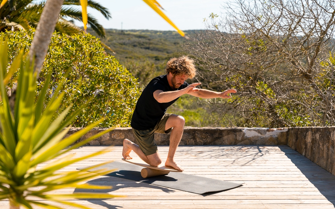 Mann beim Surfworkout auf Balance Board aus Holz mit Korkrolle