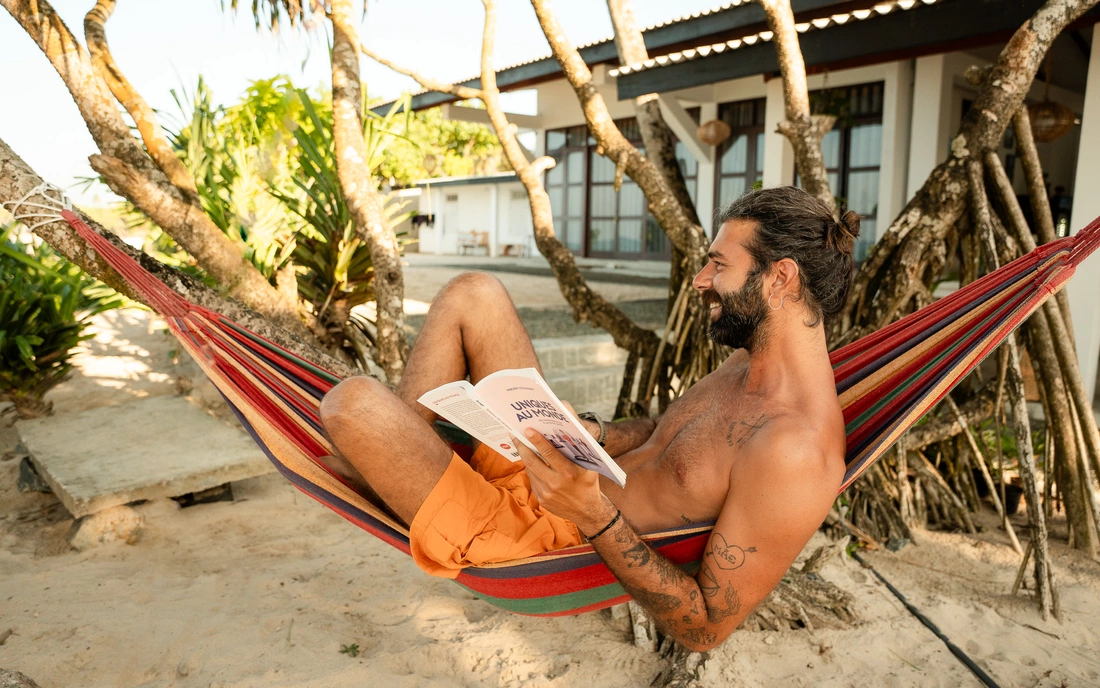 Mann liest Buch in der Hängematte