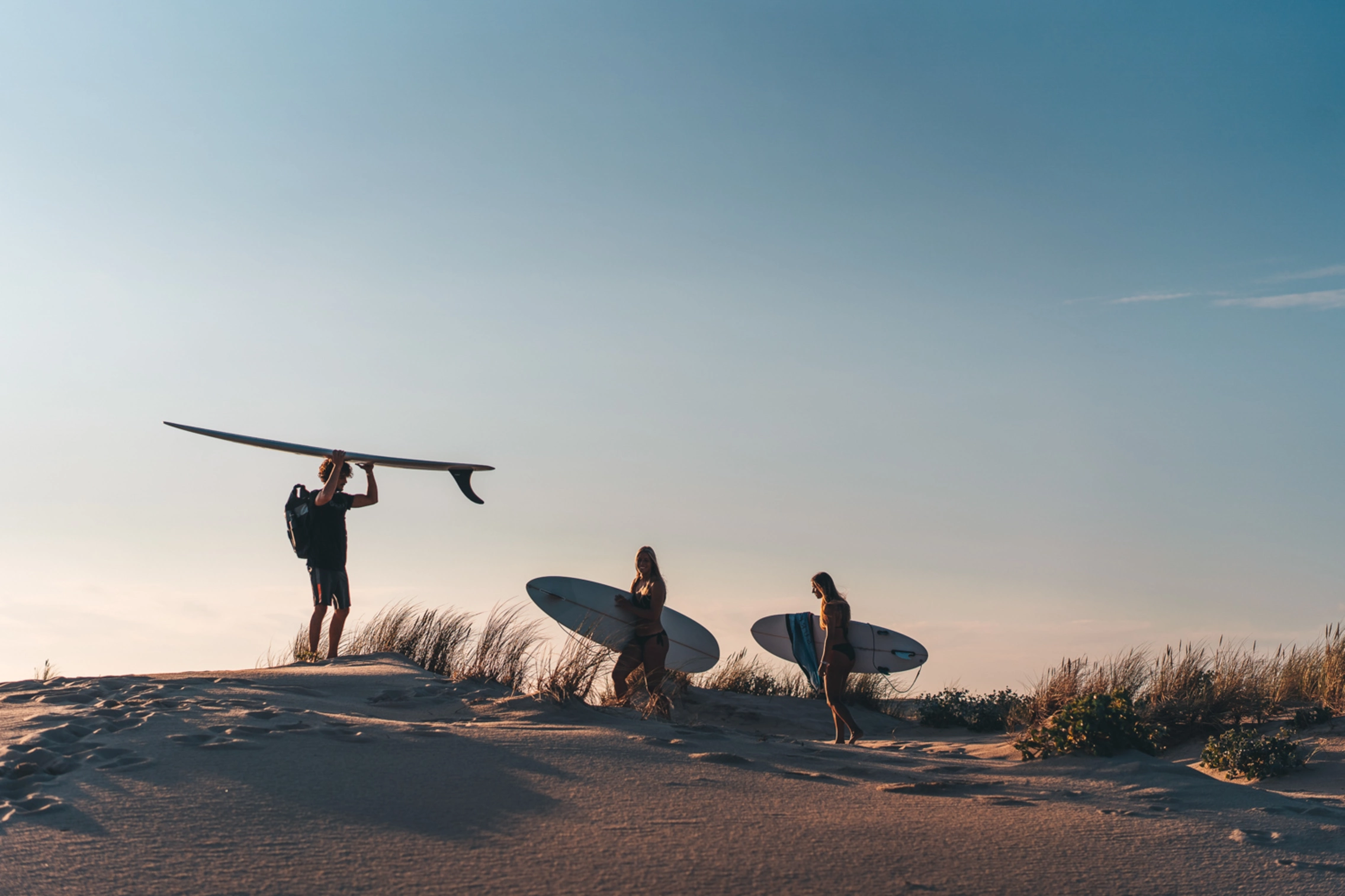 Surfer mit Surfbrett vor Sonnenuntergang