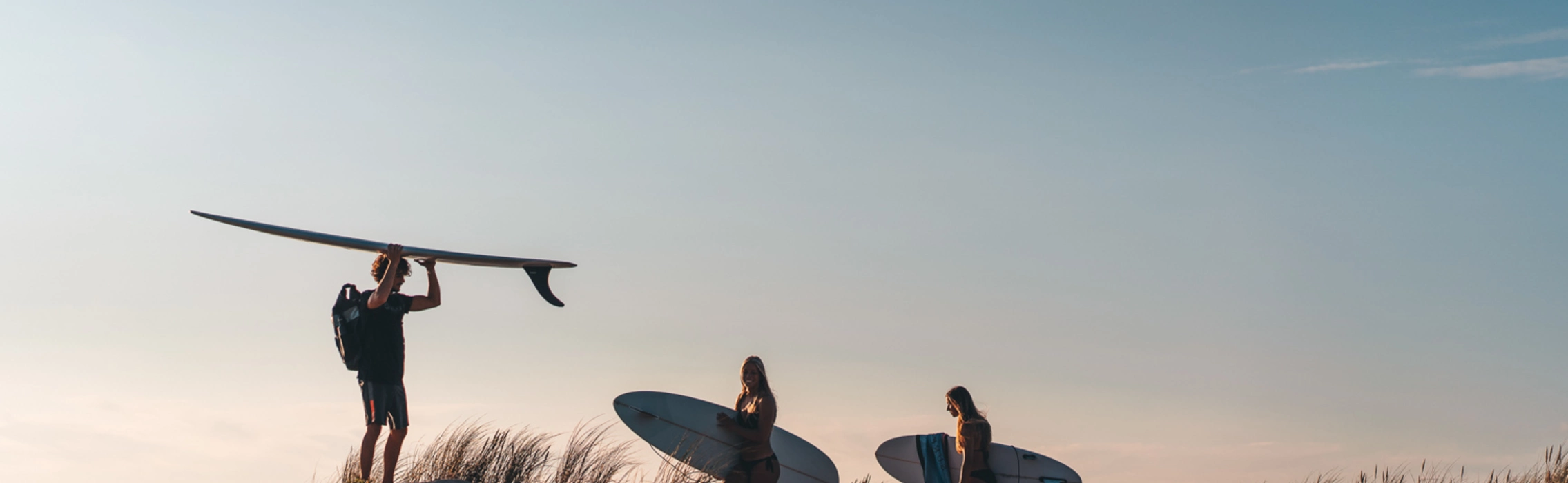 Surfer mit Surfbrett vor Sonnenuntergang