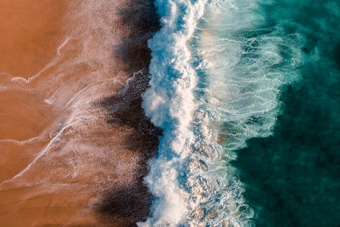 Auf den Strand brechende Welle von oben