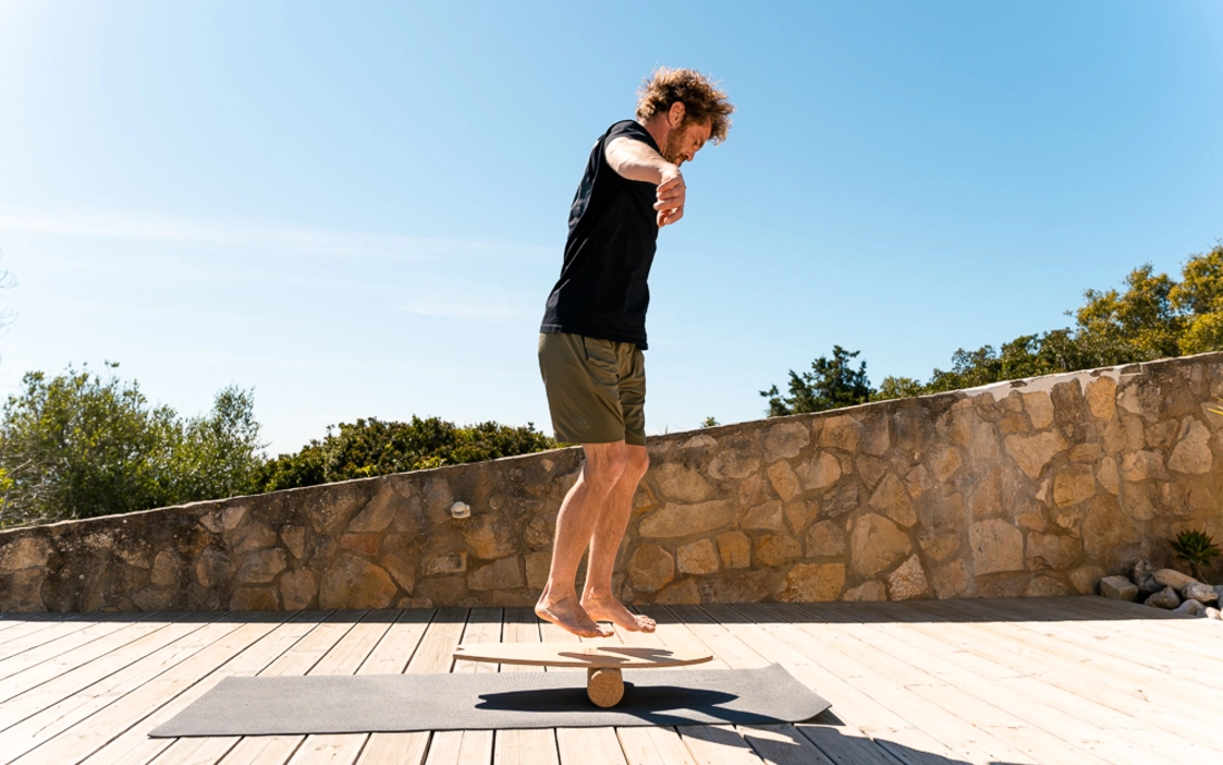 Mann beim Surfworkout auf Balance Board aus Holz mit Korkrolle