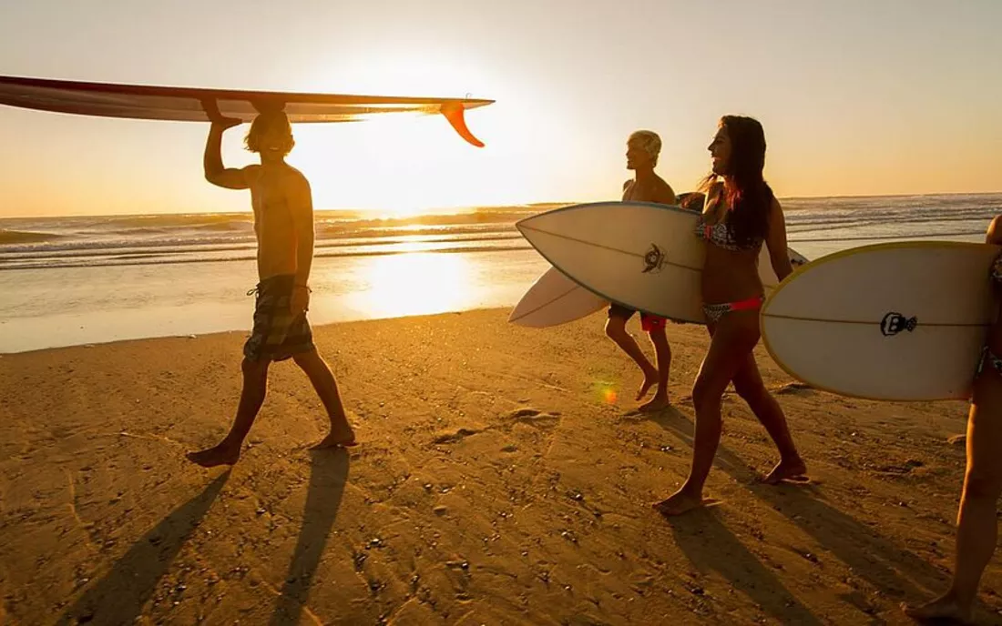 Surfer im Surfkurs auf dem Weg ins Wasser