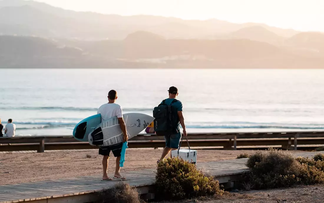 [Translate to English:] Surfer mit Surfboard am Strand