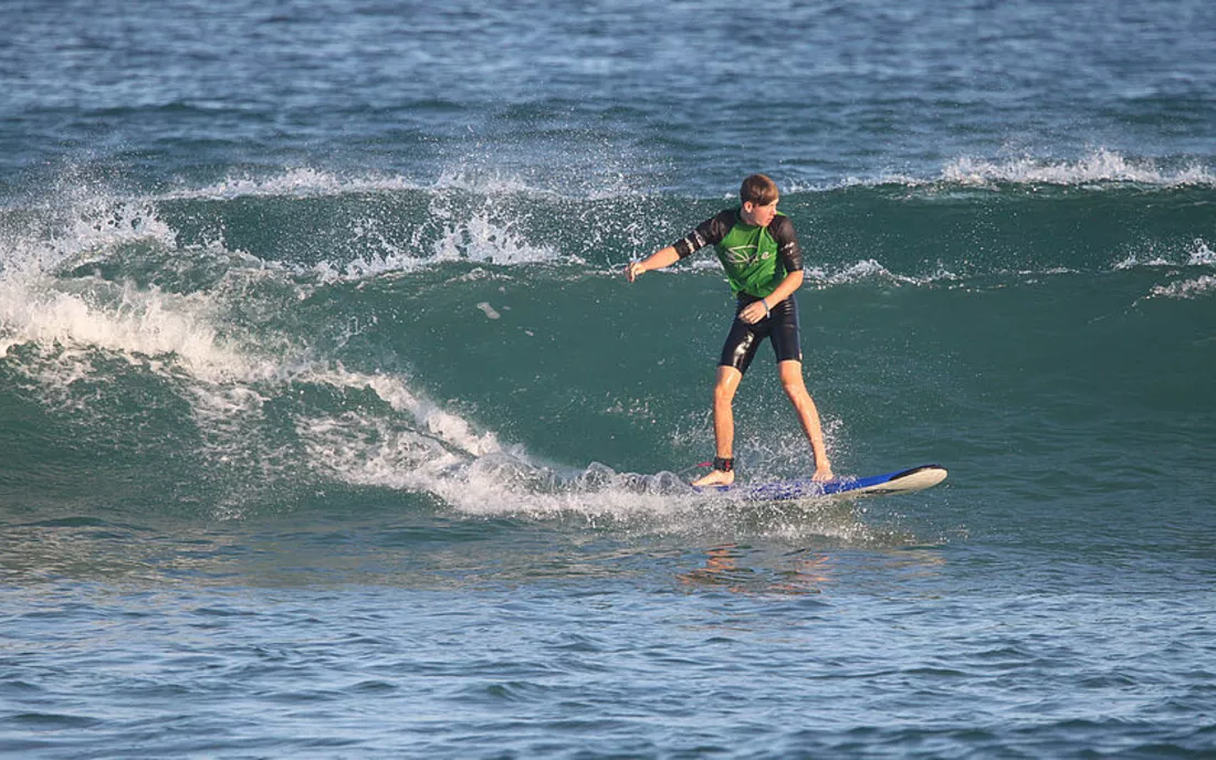 Surfer beim Surfen lernen in einer grünen Welle