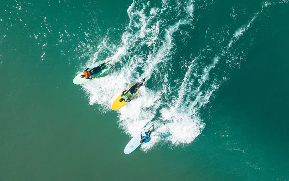 Surfkurs im Wasser beim Wellen anpaddeln