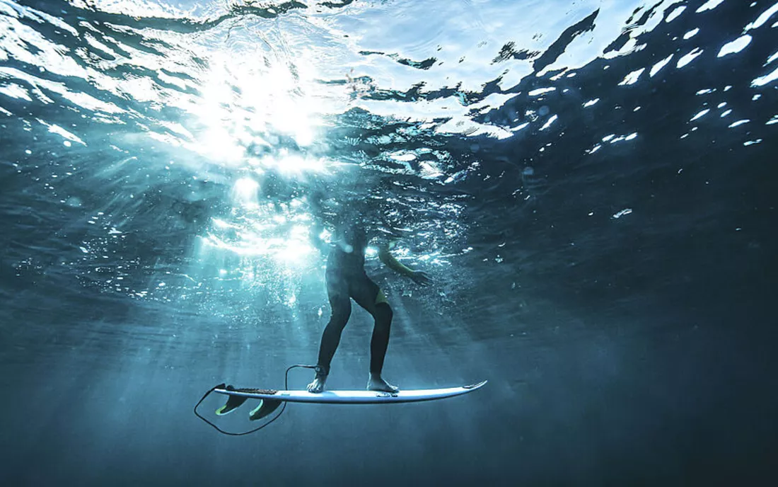 Surfer beim Surfen mit Surfbrett Unterwasser