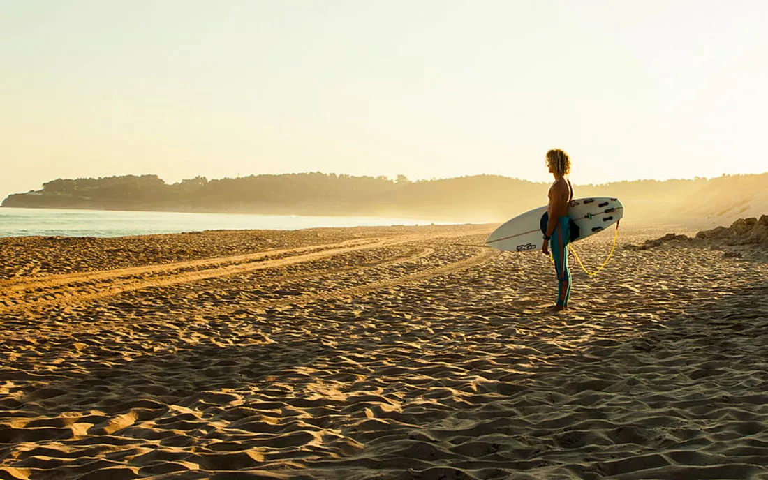 Surfer mit Surfbrett am Strand in Spanien