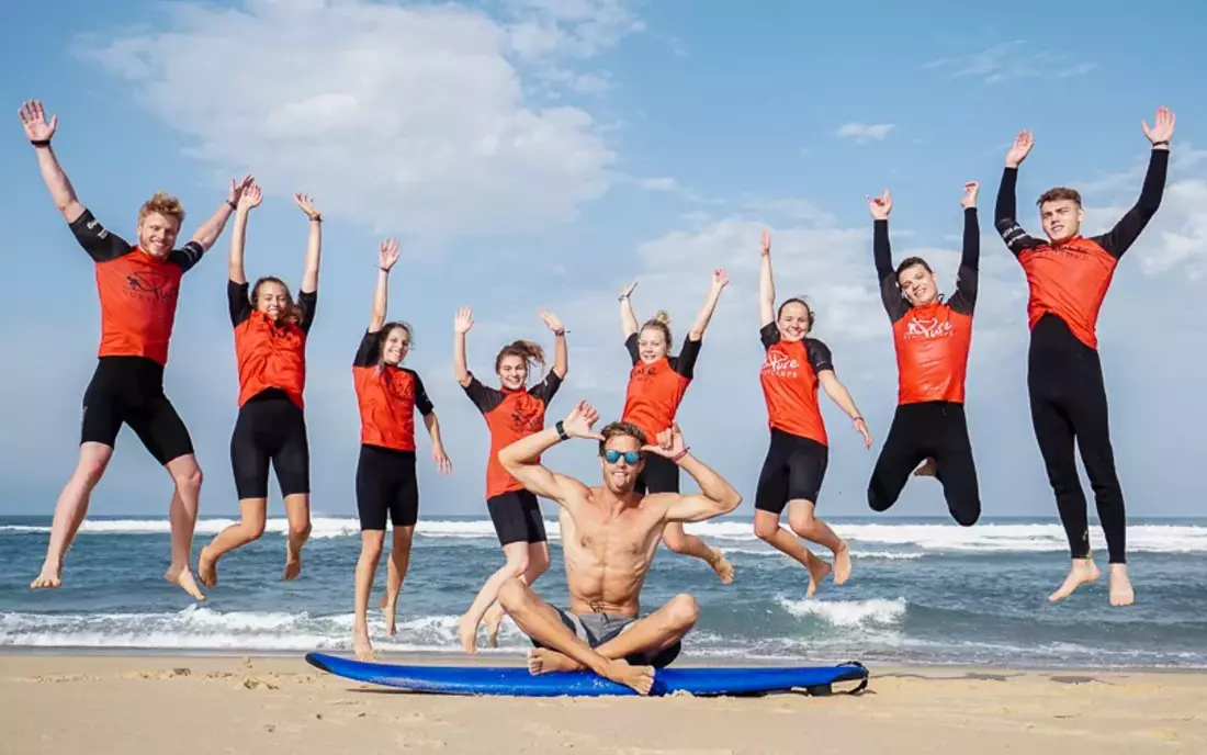 Surfkurs mit Surflehrer beim Gruppenfoto am Strand