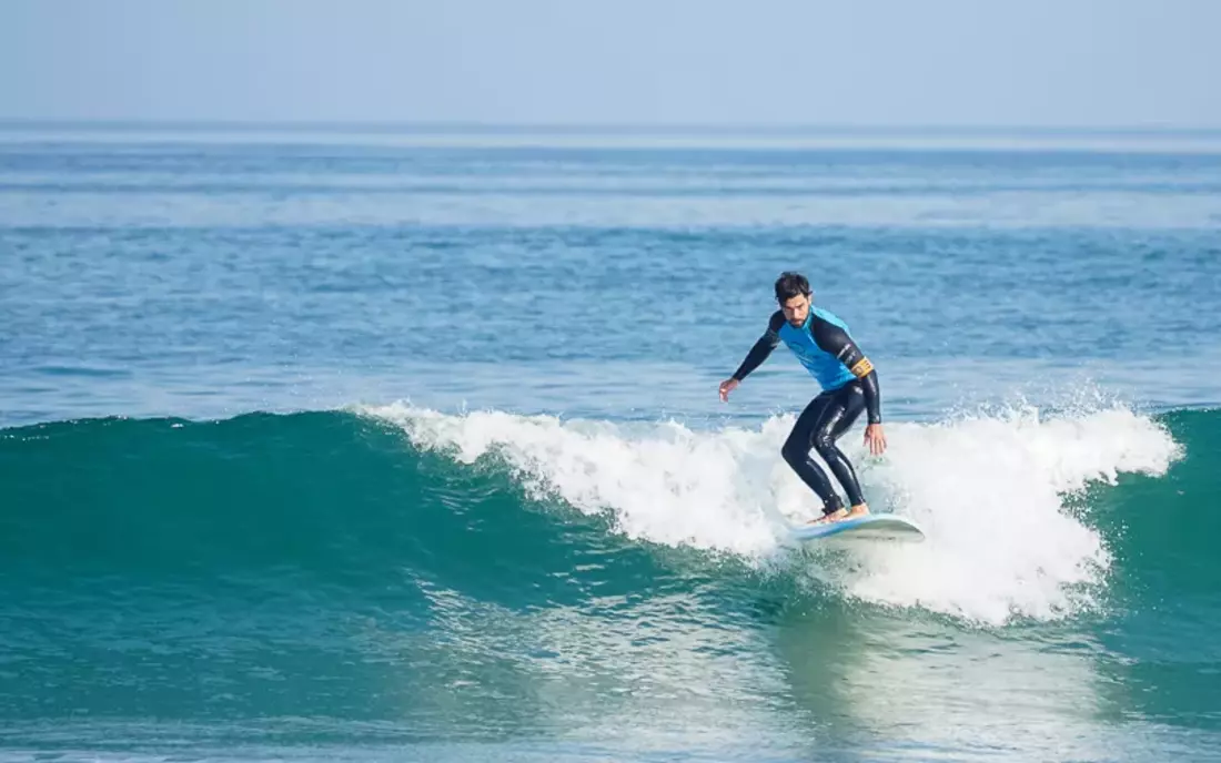 Surfer surft im Surfkurs eine grüne Welle