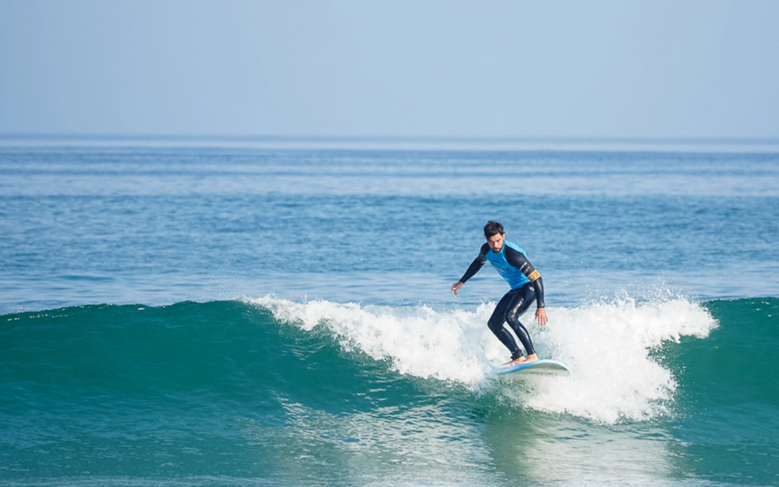 Surfer surft im Surfkurs eine grüne Welle