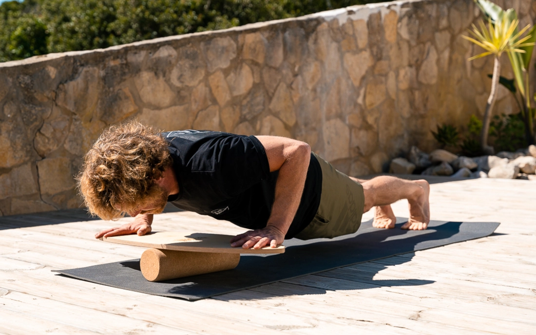 Mann übt Liegestütz auf Balance Board auf Rolle aus