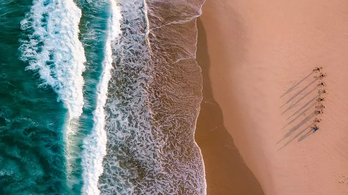 Drohnenaufnahme Surfer stehen am Wasserrand 