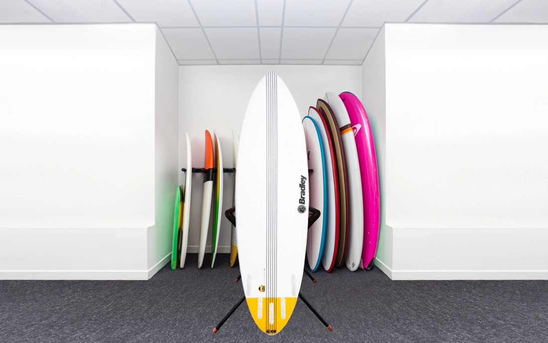 Weißes Summer Shortboard Surfbrett vor einer Reihe Surfboards