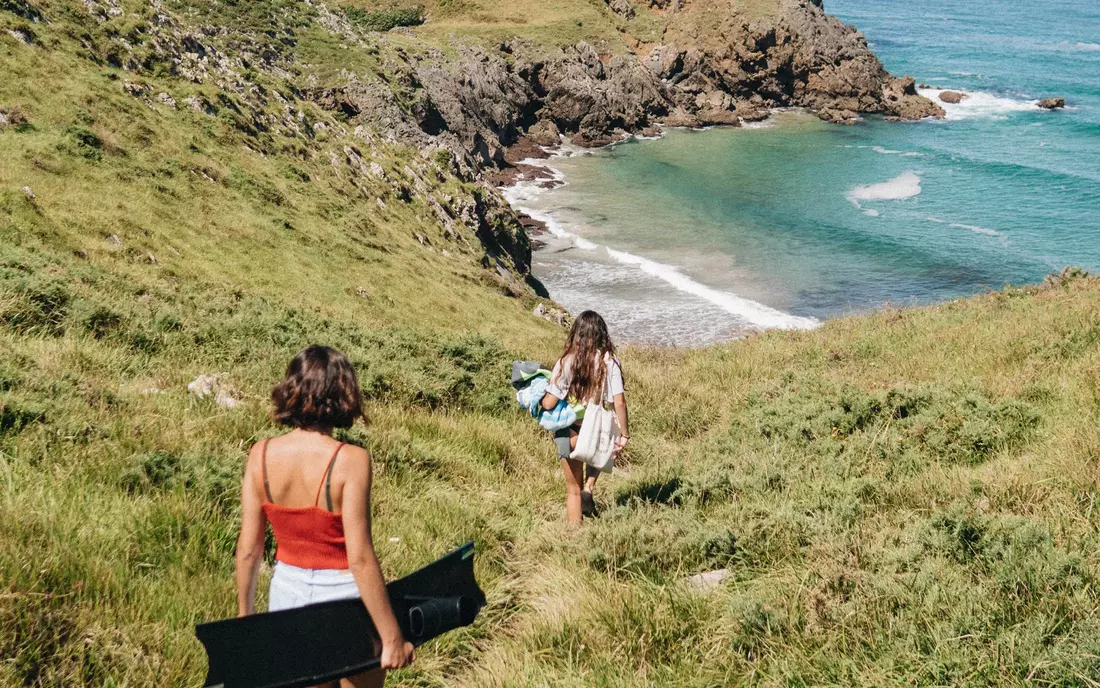 Zwei Frauen auf dem Weg zu einer Bucht, umgeben von Wiese