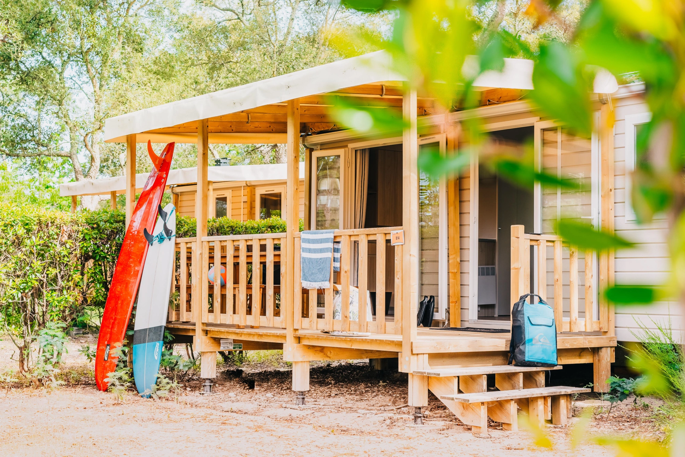 Mobile Home mit Holzterrasse im Pure Surfcamp Moliets unter Bäumen