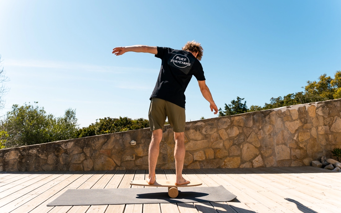 Mann beim Surfworkout auf Balance Board aus Holz mit Korkrolle