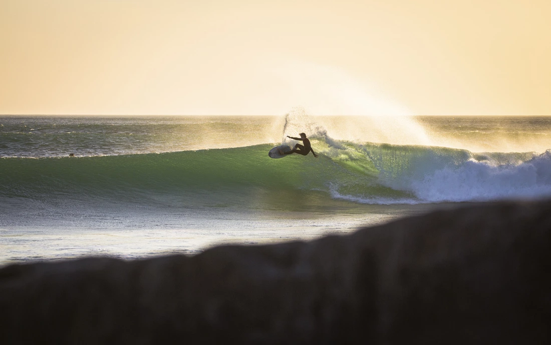 surfer surfing wave during sunset in morocco