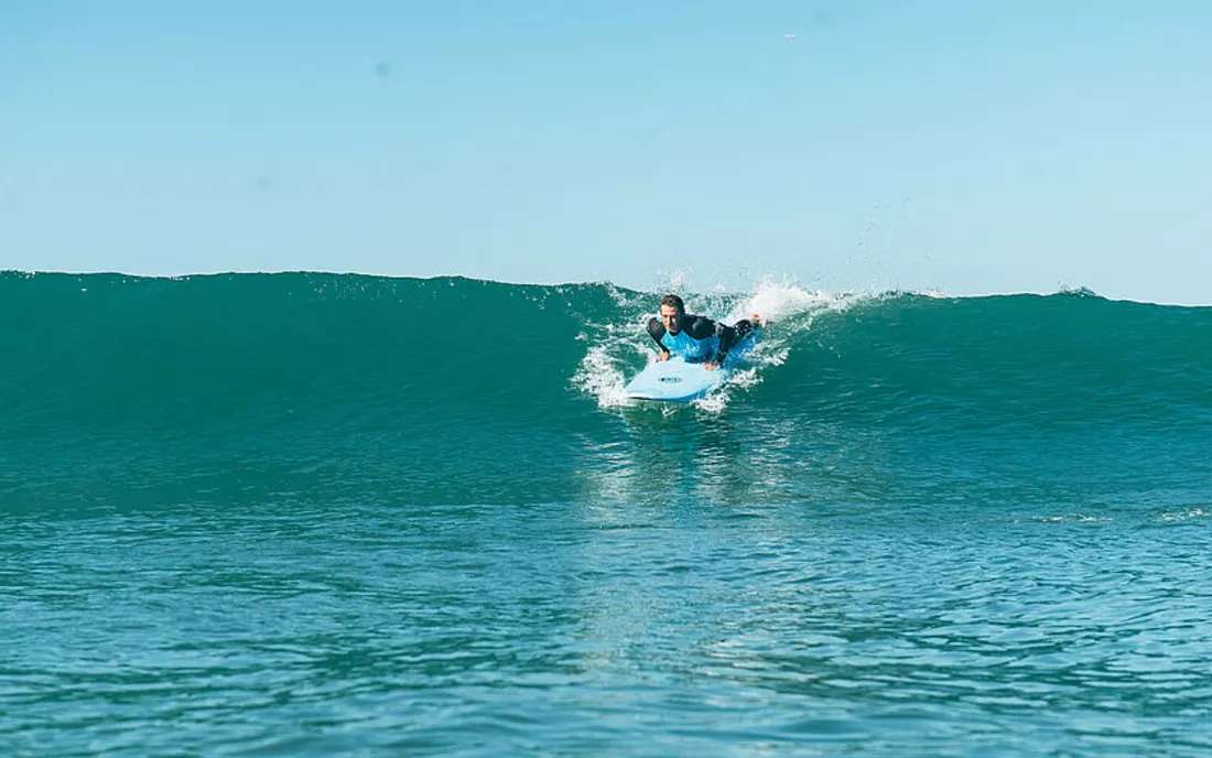 Surfer im Surfkurs startet in eine Welle