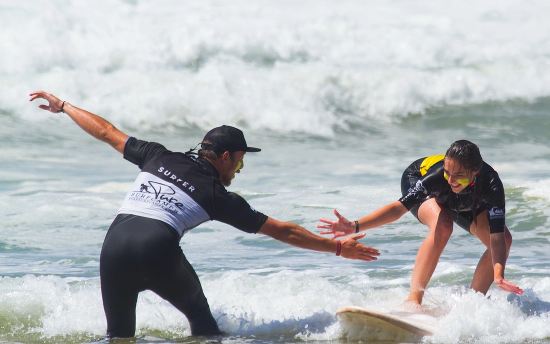 surf instructor teaching surf student in the water