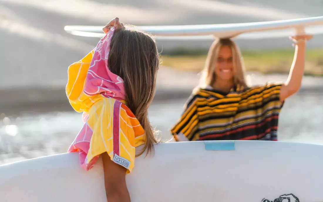 Surferinnen im Surf Poncho und mit Surfbrett am Strand