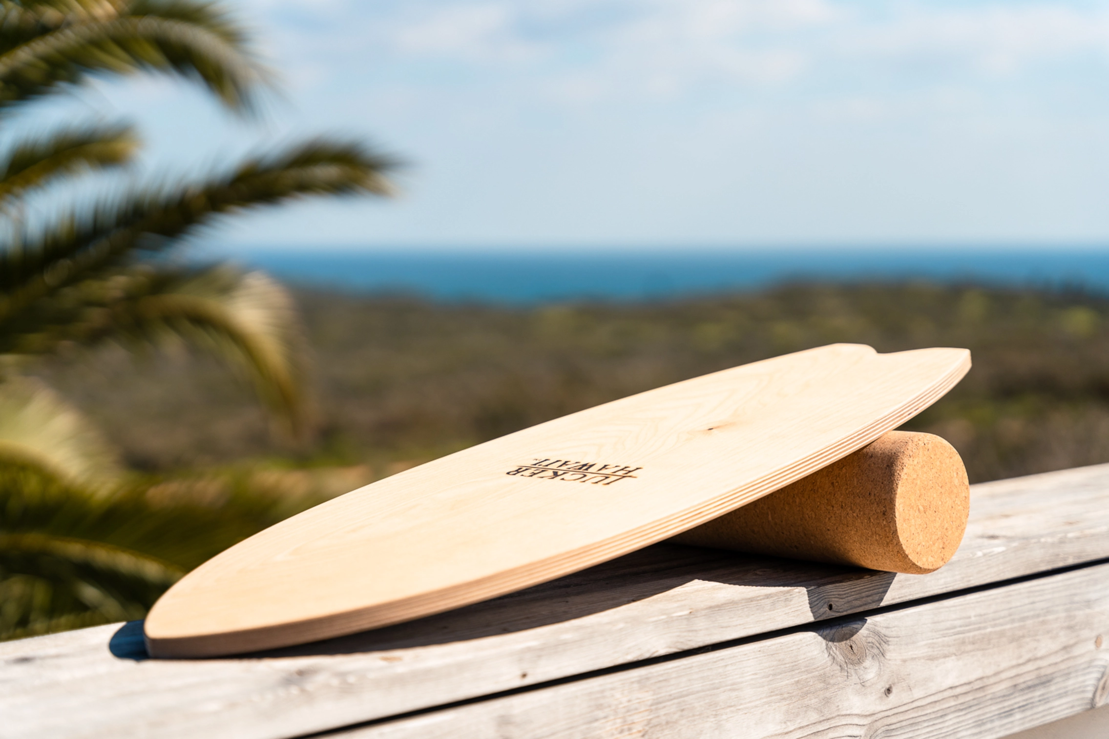 Balance Board aus Holz auf Korkrolle mit Meer im Hintergrund